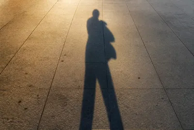 Outdoor photo with a person-shaped shadow on pavement for the AI Shadow Remover