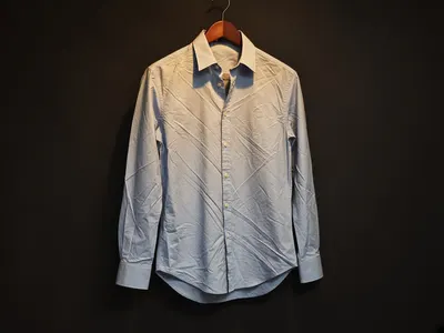 Shirt on a hanger before using the Clothes Wrinkle Remover, with hard creases across the front