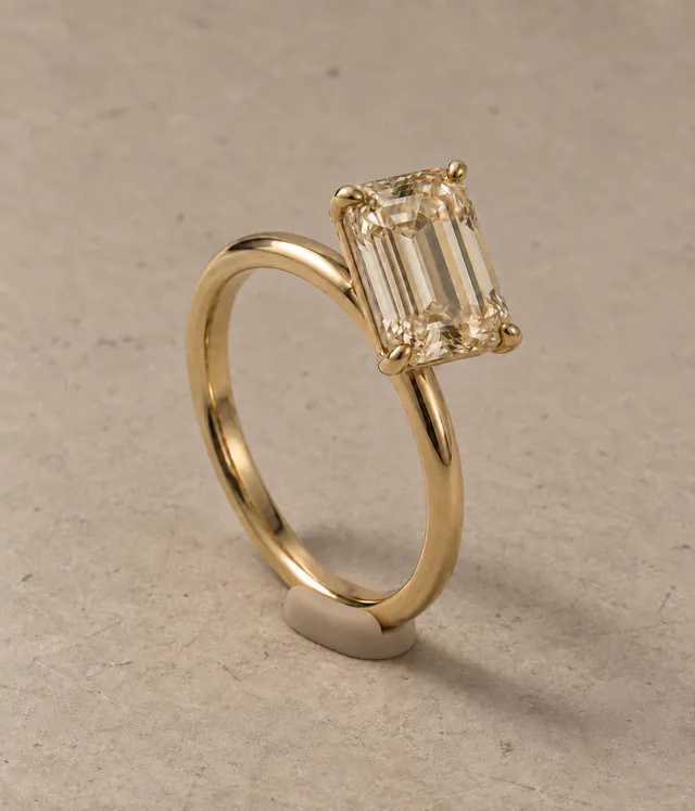 A champagne diamond ring held upright by a small beige silicone support